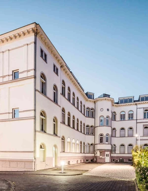 Moderne Au&szlig;enansicht der Oberberg Tagesklinik Frankfurt am Main &ndash; helles Geb&auml;ude mit gro&szlig;em Eingangsbereich, Glasfront im Vordergrund
